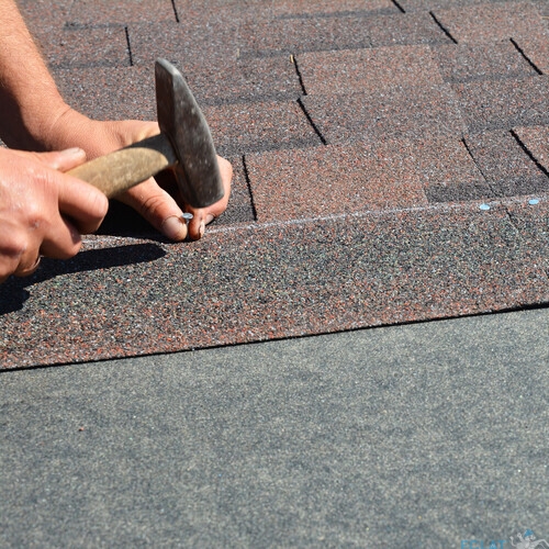 Roofing contractor installing roof tiles, asphalt shingles with copy space.