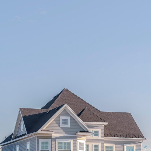 Square Modern upper floor of a grey timber house with white surrounds on the windows against a blue sky