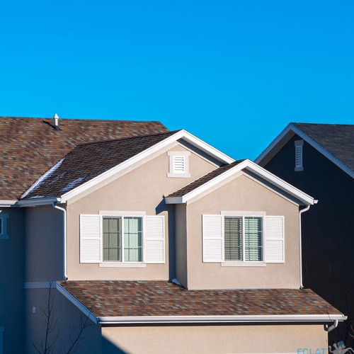 Modern house upper floor with shutters on windows in evening light against a blue sky