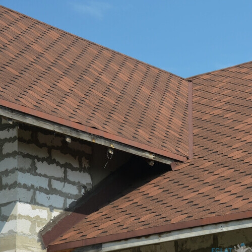 Brown asphalt shingled roof valley leaking problem area with a ventilation cap. A close-up of asphalt shingles installed on a roof valley with a waterproof flashing. Asphalt shingles roofing.