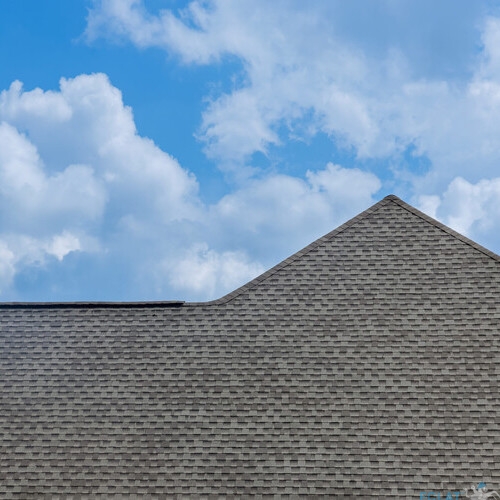 Construction roof of a house is being covered with asphalt shingles while building