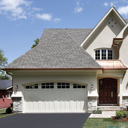 Front view of luxury home with arched entry and shingle roof
