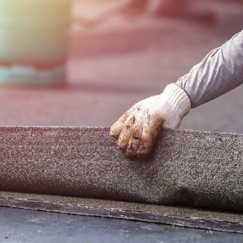 Contractor picking up a piece of EPDM roofing